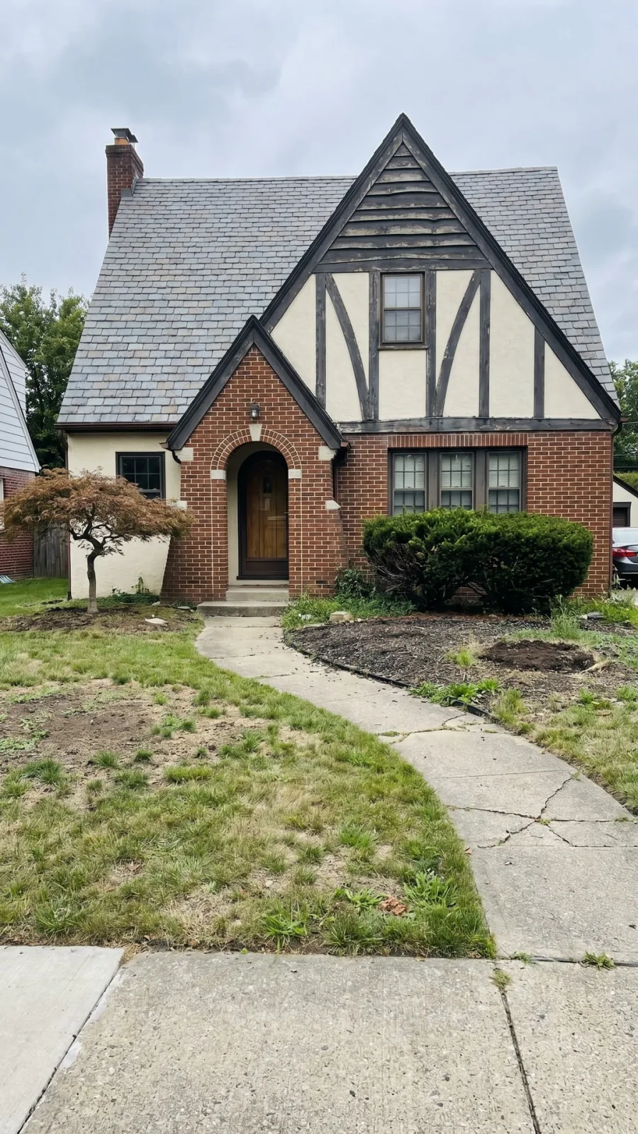 Before photo of a storybook cottage front yard with thin planting and open soil